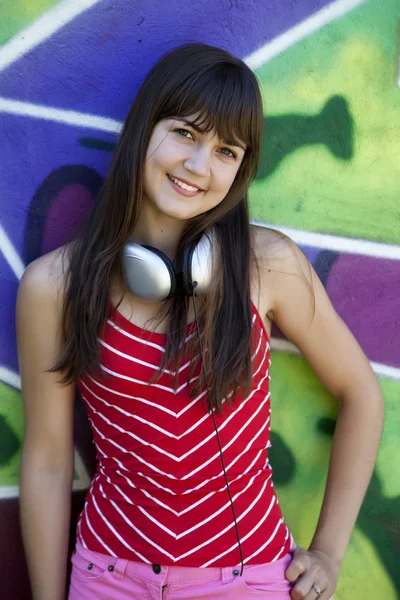 Красива брюнетка дівчина з навушниками і стіною графіті на спині — стокове фото