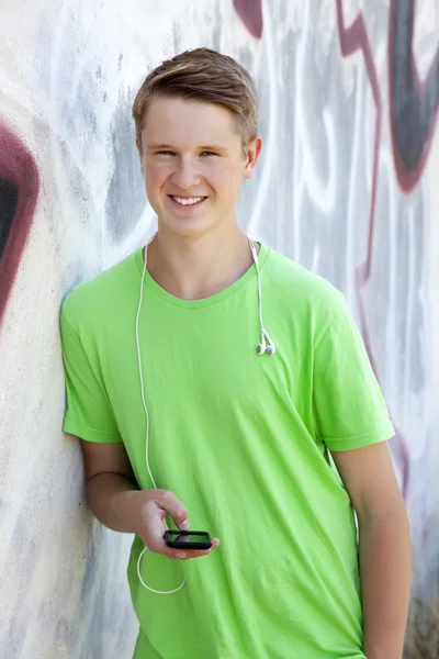 Niño adolescente con auriculares cerca de la pared de graffiti . — Foto de Stock