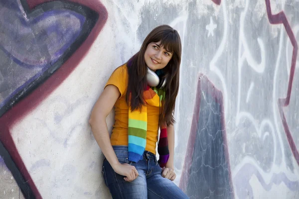 Belle fille brune avec écouteurs et mur de graffiti à bac — Photo