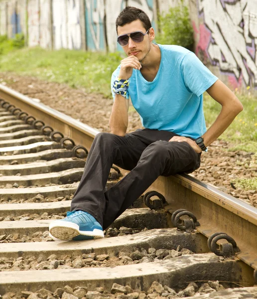 stock image Young boy in glasses sitting at railway.