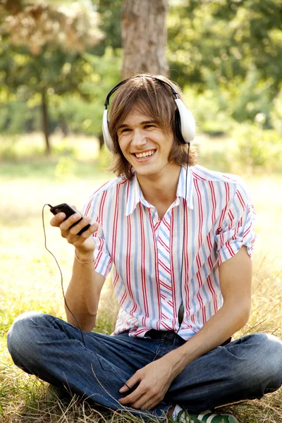 Усміхнений красивий чоловік з навушниками на відкритому повітрі — стокове фото