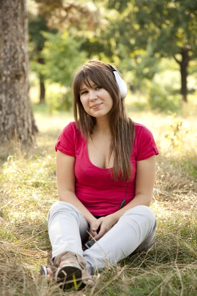 Brunette meisje met hoofdtelefoon in het park. — Stockfoto