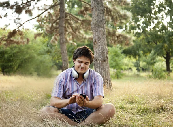 Lachende knappe man met hoofdtelefoon in de open lucht — Stockfoto