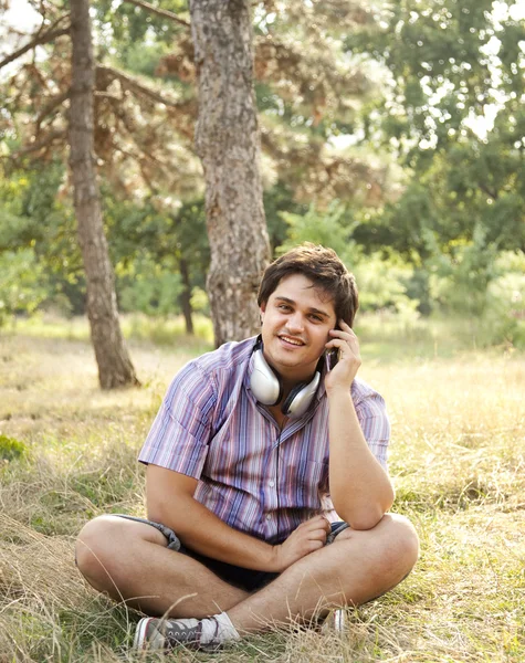 Un bel homme souriant avec des écouteurs à l'extérieur — Photo