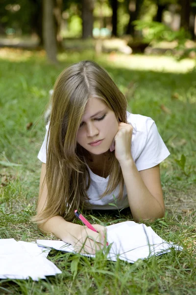 Blond meisje huiswerk in het park. — Stockfoto