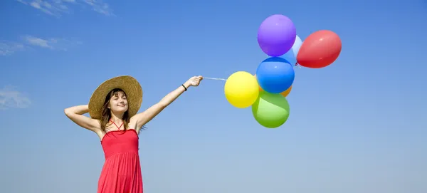 Brunett tjej med färg ballonger på blå himmel bakgrund. — Stockfoto