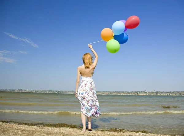 Roodharige meisje met kleur ballonnen aan kust. — Stockfoto