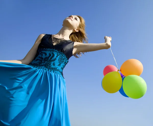 Руда дівчина з кольоровими кульками на фоні блакитного неба . — стокове фото