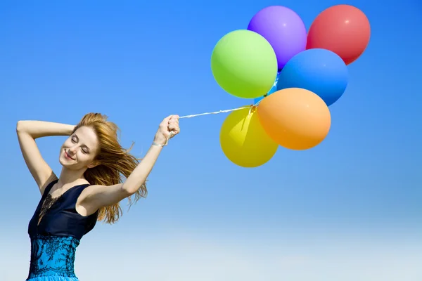 Pelirroja chica con globos de color en el fondo del cielo azul . — Foto de Stock