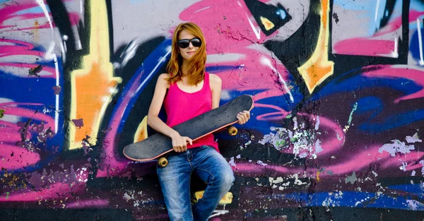 Style girl with skateboard near graffiti wall. — Stock Photo, Image