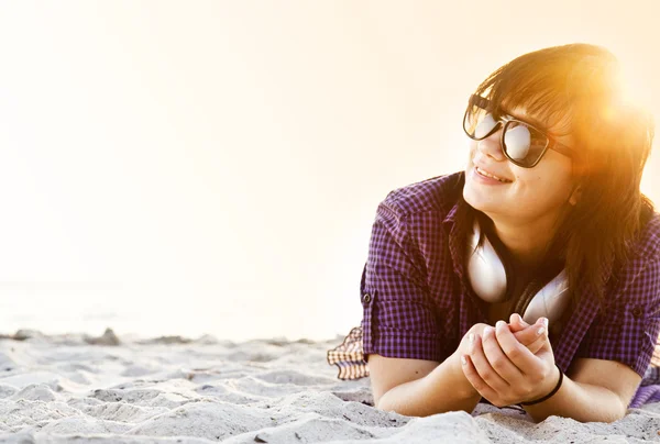 Piękna brunetka dziewczyna ze słuchawkami w piasku na plaży. — Zdjęcie stockowe