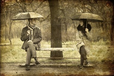 Two sitting at bench in rainy day. Photo in old image style. clipart