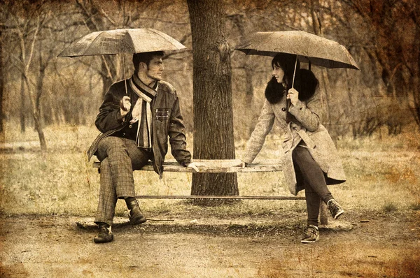 Two sitting at bench in rainy day. Photo in old image style. — Stock Photo, Image