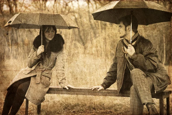 两个在下雨天坐在长凳。旧图像样式的照片. — 图库照片