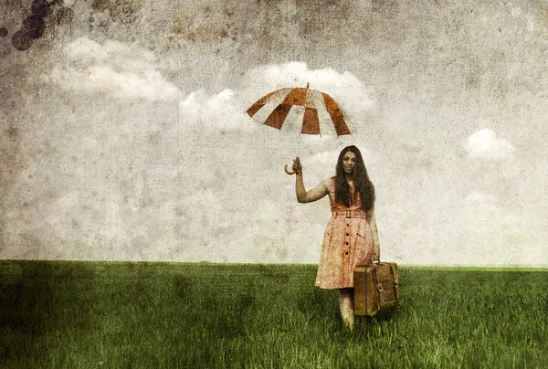 Чародейка с зонтиком и чемоданом на весеннем рапсе — стоковое фото