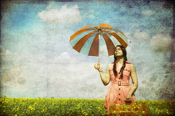 Чародейка с зонтиком и чемоданом на весеннем рапсе — стоковое фото