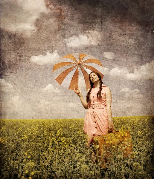 Brünette Zauberin mit Regenschirm und Koffer bei Frühlingsrapese — Stockfoto