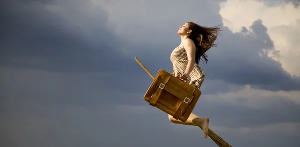 Young brunette witch on broom flying away — Stock Photo, Image