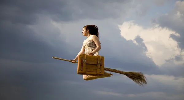 Young brunette witch on broom flying away — Stock Photo, Image