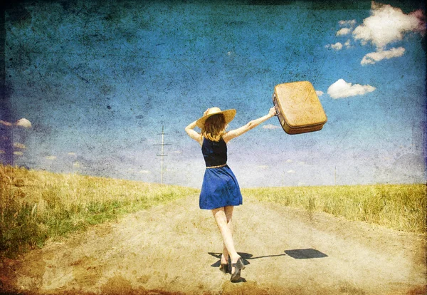 Одинокая девушка с чемоданом на проселочной дороге . — стоковое фото