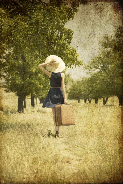 Κοκκινομάλλα κοπέλα με βαλίτσα σε χώρα. — Φωτογραφία Αρχείου