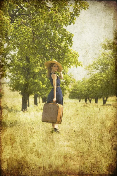 Rothaarige Mädchen mit Koffer auf dem Land. — Stockfoto