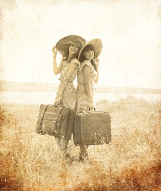 Two retro style girls with suitcases at countryside. clipart