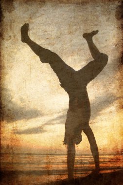 Acrobatic men at the beach at sunset. clipart