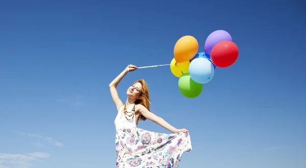 Kızıl saçlı kız mavi gökyüzü arka plan, renk balonlar ile. — Stok fotoğraf