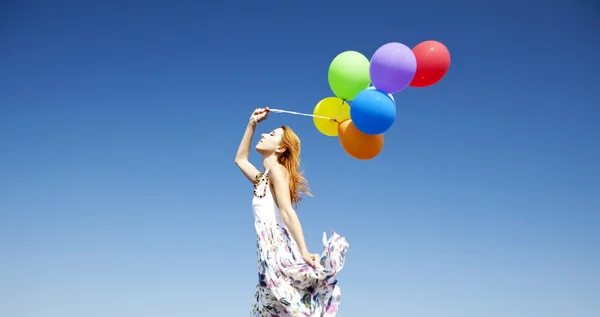 Rothaarige Mädchen mit bunten Luftballons am blauen Himmel Hintergrund. — Stockfoto