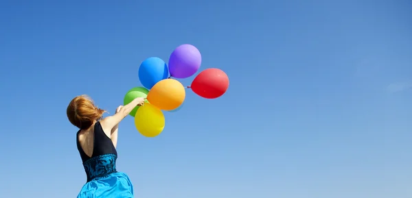 Fille rousse avec des ballons de couleur à fond bleu ciel . — Photo