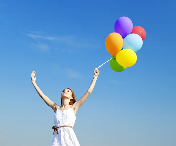 Rusovláska dívka s barevné balónky na pozadí modré oblohy. — Stock fotografie