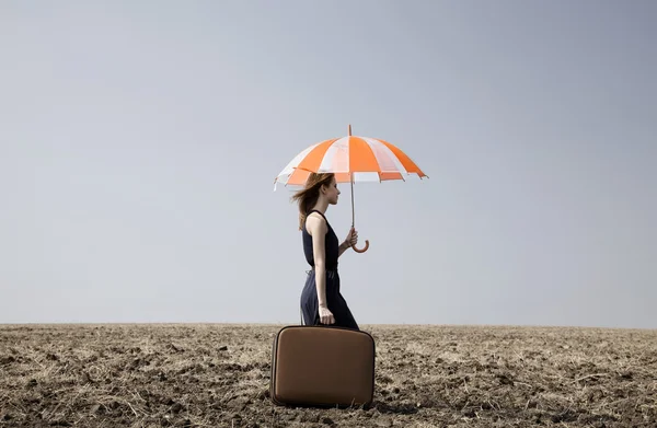 Redhead girl with umbrella at windy field. — Stock Photo, Image