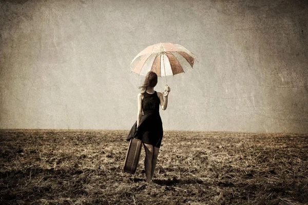 Rusovláska dívka s deštníkem na větrné pole. — Stock fotografie