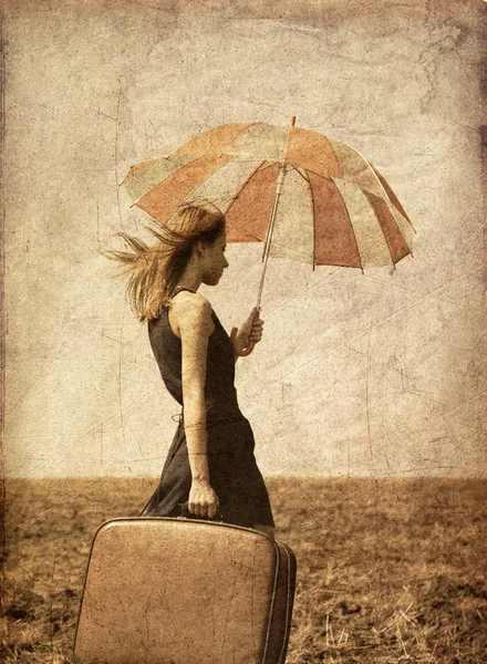 Rothaarige Mädchen mit Regenschirm auf windigem Feld. — Stockfoto