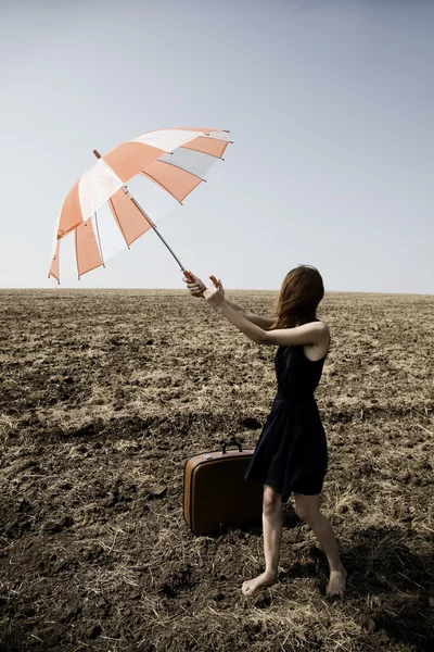 Roodharige meisje met paraplu op winderige field. — Stockfoto