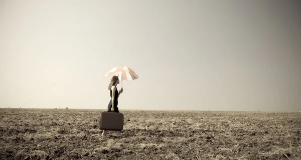 Vöröshajú lány esernyő a szeles field. — Stock Fotó