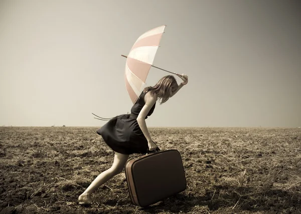 Рыжая девушка с зонтиком на ветреном поле . — стоковое фото