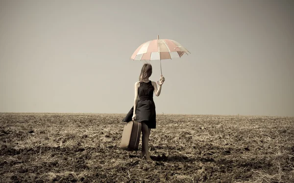 Rothaarige Mädchen mit Regenschirm auf windigem Feld. — Stockfoto