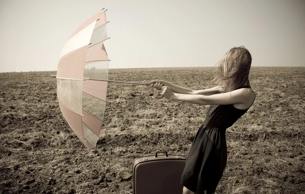 Rusovláska dívka s deštníkem na větrné pole. — Stock fotografie