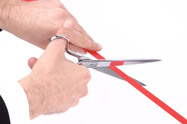 Mãos de homem cortando uma fita vermelha com tesoura — Fotografia de Stock
