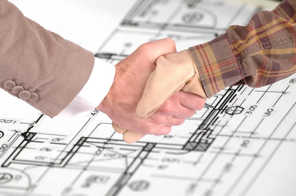 Arbeiter und Geschäftsmann schütteln Hände über Renovierungspläne — Stockfoto