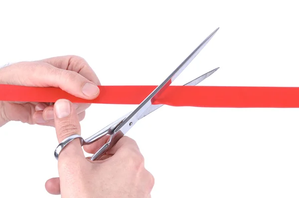 Primer plano de una mano de hombre cortando una cinta roja con tijeras — Foto de Stock
