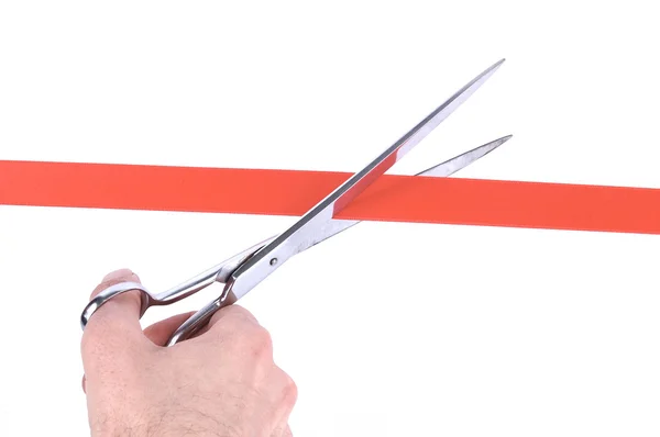 Ręka mężczyzny cięcia czerwoną wstążką z nożyczkami — Zdjęcie stockowe