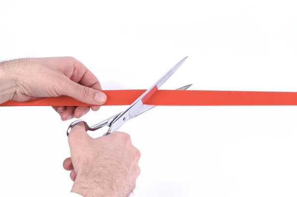 Mão de homem cortando uma fita vermelha com tesoura — Fotografia de Stock