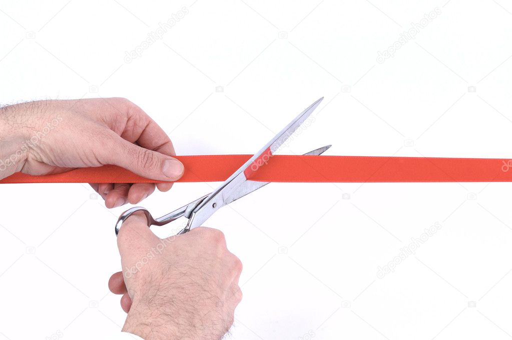 Man's hand cutting a red ribbon with scissors