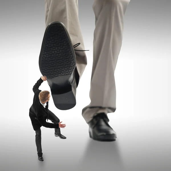 Piccolo uomo d'affari schiacciato dai piedi di un cespuglio gigante — Foto Stock