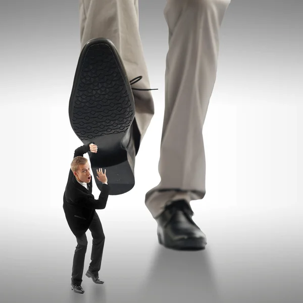 Pequeño hombre de negocios siendo aplastado por los pies de un negocio gigante — Foto de Stock
