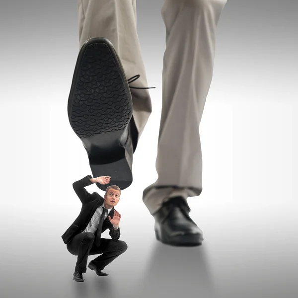 Pequeño hombre de negocios siendo aplastado por los pies de un negocio gigante — Foto de Stock