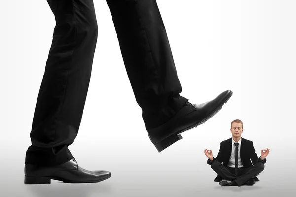 Little business man being crushed by the feet of a giant busines — Stock Photo, Image